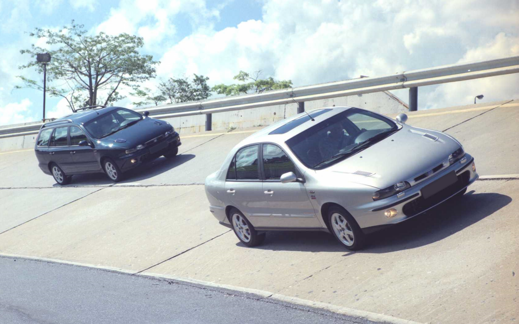 Dois carros Fiat Marea preto e prata correndo na estrada.