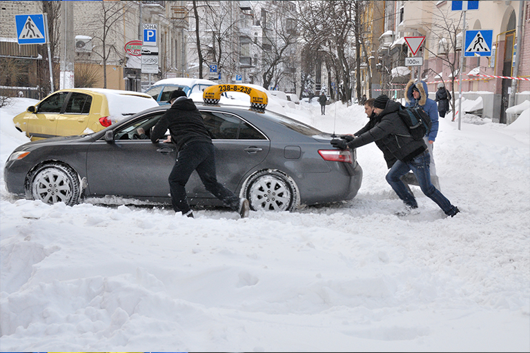 Homens empurrando carro na neve
